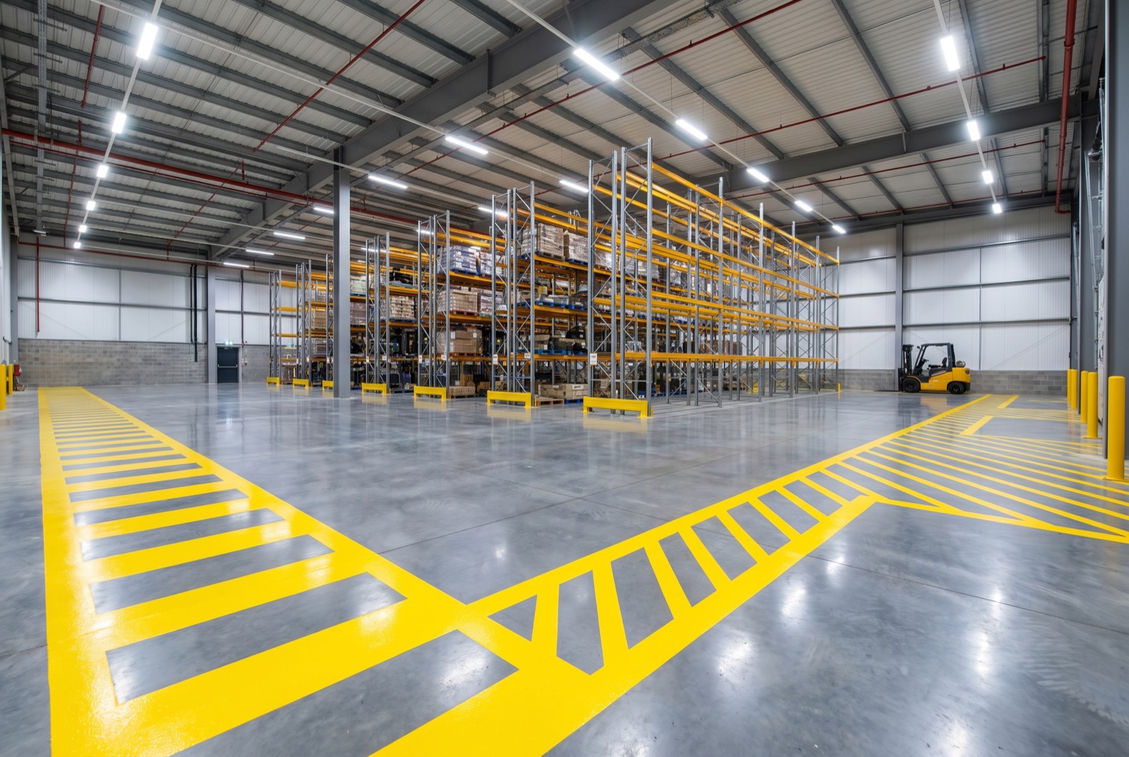 Warehouse interior with fresh yellow safety aisle and walkway striping on polished concrete